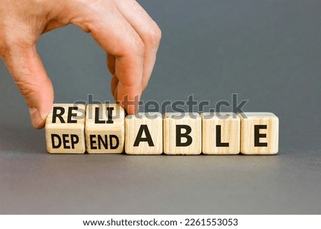 Dependable or reliable symbol. Businessman turns wooden cubes and changes the word dependable to reliable. Beautiful grey background, copy space. Business and dependable or reliable concept.