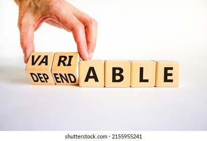 Dependable or variable symbol. Businessman turns wooden cubes and changes the word dependable to variable. Beautiful white background, copy space. Business and dependable or variable concept.