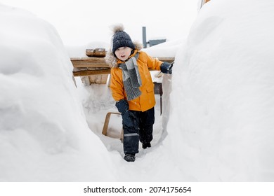Depiction of a happy child of five six years old playing in a snowdrift in the winter and posing for the camera. Happy childhood