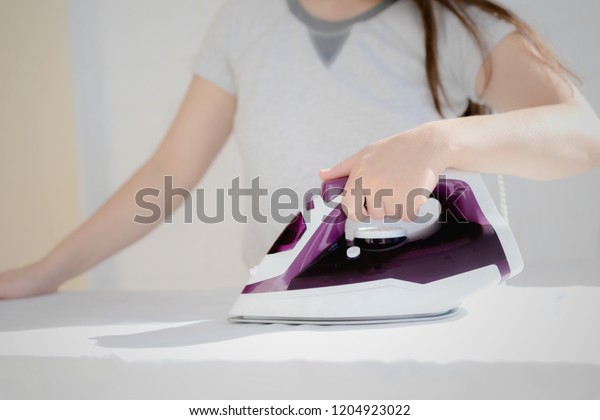 depicts the process of ironing clothes, visible\
iron, clothes, ironing\
board