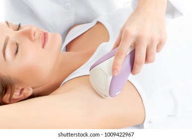 Depilation. Beautician giving epilation laser treatment to woman on underarm