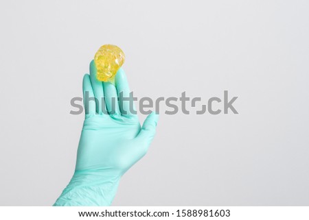 Depilation and beauty concept, sugar paste or wax honey for hair removing on glove hand of cosmetologist on white background, copy space.