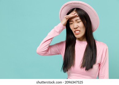 Depleted Exhausted Emaciated Knackered Sad Young Brunette Asian Woman 20s With Hand On Forehead Wears Pink Clothes Hat Isolated On Pastel Blue Color Background Studio Portrait. People Emotions Concept