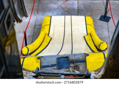 A deployed yellow inflatable emergency slide ramp extends from an airplane exit, ready for rapid evacuation