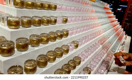 Depok, Indonesia- 08 Oct 2022. Stack Of Nail Polish On White Shelf In The City Store Accompanied With Customer Testing Deck To Please And Convince Potential Buyer