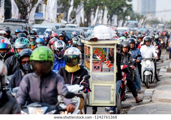 Depok, West Java/Indonesia -\
15th 09 2015: Seblak Food Street Vendot at Traffic Jam with\
Motorcycles