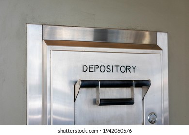 Depository sign on an exterior secured bank drop box attached to the wall of a bank building