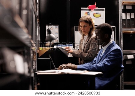 Depository workers reading administrative files, discussing bureaucracy record in storage room. Diverse bookkeepers working overtime at accountancy report, analyzing management research