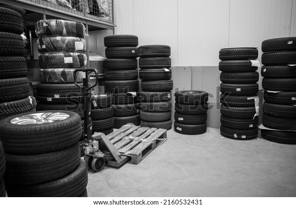 in the depot of a car repair shop
there are many summer tires ready for a wheel
change