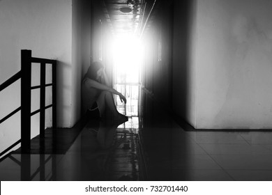 depress and hopeless woman sitting in the dark at corridor in white tone