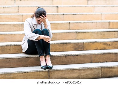 Depress woman sitting on staircase outside. Stressful white woman sitting on yellow staircase outdoor. Taken outdoor in natural lights.