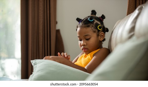 Depressed African Child Girl Kid Sitting On Sofa In Living Room. Loneliness Little Girl Living Alone Without Parent With Sadness Face And Eyes. Children Mental Health And Family Problem Issues Concept