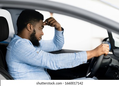 Depressed African Man Sitting In Driver's Seat Of New Too Expensive Car, Thinking Of Money Problems In Auto Dealership Store