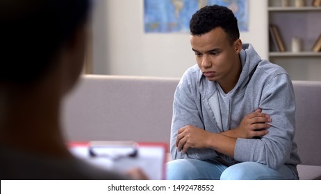 Depressed African-American teenager talking to psychologist, racism at school