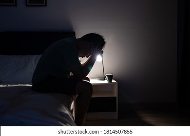 Depressed asian man crying covering face with his hands,sitting on the bed at night,Stressed worried people touching his head,suffering from grief sorrow insomnia,feel anxiety,trouble of mental health - Powered by Shutterstock