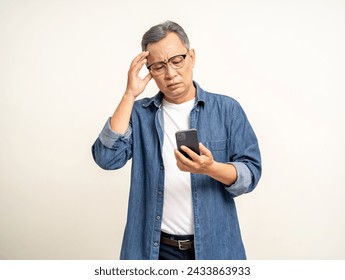 Depressed Asian mature old man standing using smartphone serious thinking on isolated background. Portrait stress of senior asian man holding cell phone. Mature People and lifestyle - Powered by Shutterstock