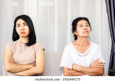 Depressed Asian Mother And Daughter Sitting At Sofa Angry, Quarrel, Ignoring Each Other , Serious Relationship In Family Concept 