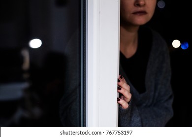 Depressed Bald Woman Sitting On The Floor Near Window At Night, Looking At Snow, Feel Tired, Afraid, Lonely And Unhappy.