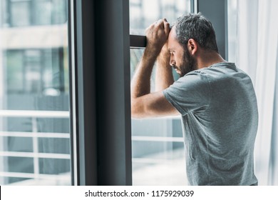 depressed-bearded-man-leaning-window-260