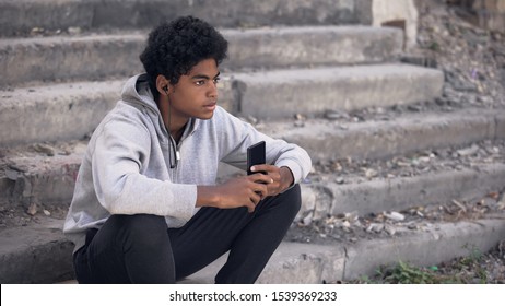 Depressed black college student listening smartphone music, emotional isolation