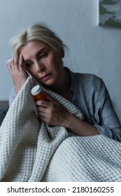 Depressed Blonde Woman With Menopause Holding Bottle With Sleeping Pills In Bed