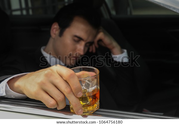 Depressed businessman has\
problem at work, drinking wisky in car. Drunk businessman fall\
asleep in car.