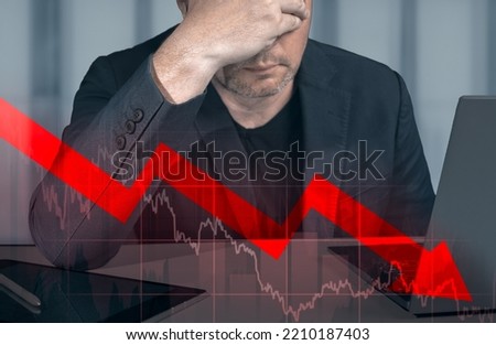 depressed businessman holding hands on bowed head, looking at declining graph. Stock market exchange loss trading graph analysis investment indicator business graph charts of financial board