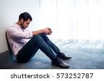 Depressed businessman sitting against a wall and looking down in studio