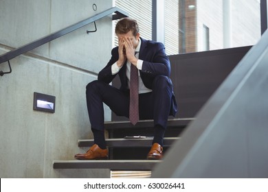 Depressed businessman sitting on stairs at office - Powered by Shutterstock