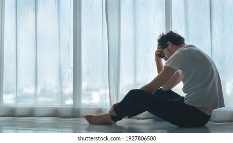 Depressed caucasian man losing job and heartbroken at same time sitting alone near window in dark at evening time with low light environment, PTSD Mental health and depression concept. - Shutterstock ID 1927806500