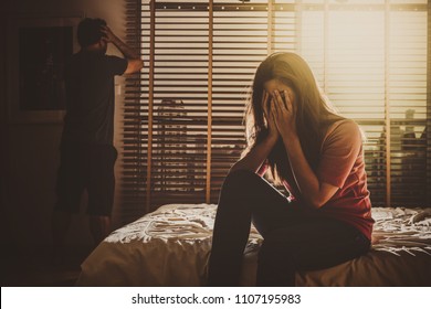 Depressed Couple Husband And Wife Sitting Head In Hands On The Bed In The Dark Bedroom With Low Light Environment, Dramatic Concept