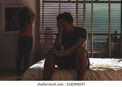 Depressed Couple Husband And Wife Sitting Head In Hands On The Bed In The Dark Bedroom With Low Light Environment, Dramatic Concept