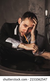 Depressed Crazy Man Writer With Pen In Mental Health In Bathtub In Bathroom. Problem Creative Person Showing Human Emotions. Concept Apathy, Anxiety, Illness, Trouble, Creative Decline