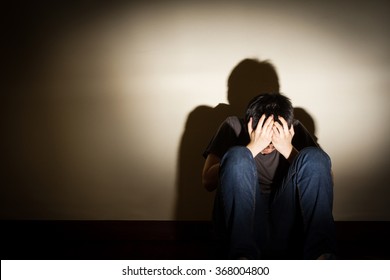 depressed despaired young man sit on the floor hiding his face, vignette effect