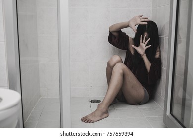 depressed fear woman hearing family violence or Couple or husband and wife or Thief or robber sitting on bathroom floor and holding head feeling afraid in dark with battered abused woman concept.