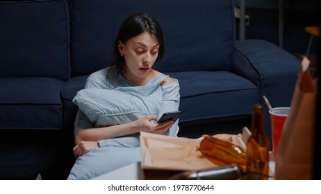 Depressed Hopeless Lonely Woman Overwhelmed By Problems Browsing On Phone, Reading Shocked Digital Eviction Notice Sitting On Floor Holding Pillow. Worried Tenant Reading Notification For Unpaid Bills