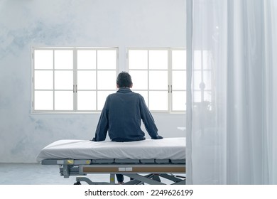 Depressed inpatient sitting on bed in hospital room - Shutterstock ID 2249626199