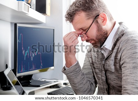 Depressed investor analyzing crisis stock market with charts on laptop screen at home office