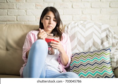 Depressed Latin Woman Sad Eating Chocolate Ice Cream And Staring At It With Guilt