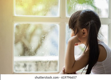Depressed Little girl  near window at home, closeup