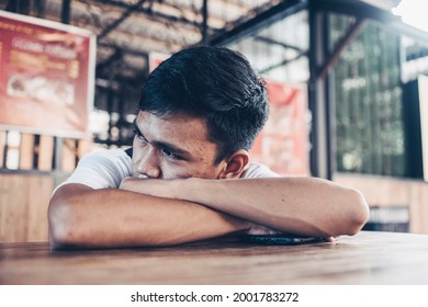 A Depressed And Lonely Teen Lying On The Table At A Outdoor Food Court. Low Self Esteem From Facial Acne.