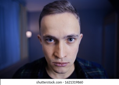 A Depressed Look On The Face Of A Young Caucasian Man With Gray Eyes And A Short Haircut. Paranoid White Male In A Dark Blue Room. The Guy Is 22 Years Old With A Crazy Gaze.