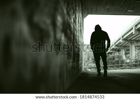 Depressed looking silhouette of a man walking in tunnel