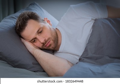 Depressed Man Having Insomnia Unable To Sleep Lying In Bed In Bedroom At Home At Night. Sleeplessness, Mental Health Problem, Male Depression Concept. Low Light