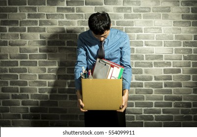 depressed man holding box in his hands, with office supplies inside, wall background - Shutterstock ID 554099911