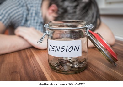 Depressed Man Lying On Table. Pension Savings In Jar In Front.