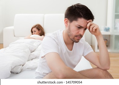 Depressed Man Sitting On The Edge Of The Bed In Bedroom