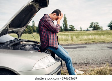 Depressed Man Sitting On A Hood Of Broken Car