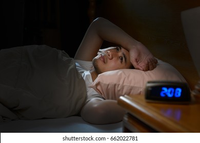 Depressed man suffering from insomnia lying in bed - Shutterstock ID 662022781