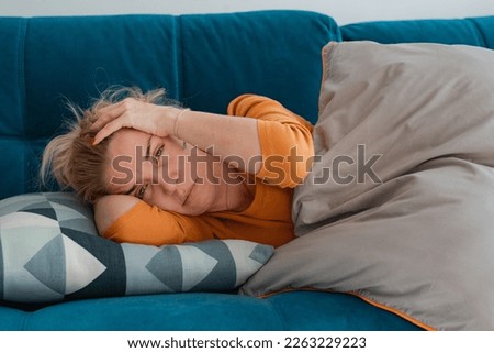 depressed mature woman lying sofa with her arms around herself, covering her head with hands, unhappy woman suffering from insomnia depression, psychological problem, concept impotence, asthenia